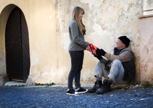 Millennial woman giving homeless man a gift