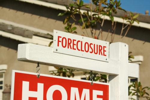 Foreclosure sign above a “home for sale” sign