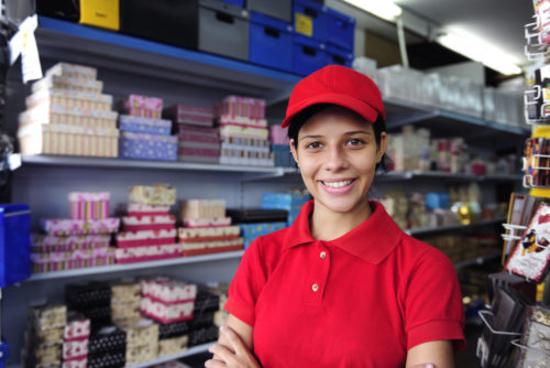 A high school student in a red uniform working at a convenience store