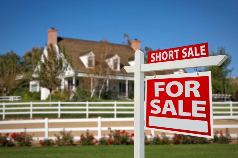 A house with a for sale sign in front, announcing a short sale