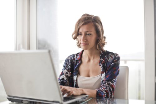 Woman in a blue floral top sitting at a laptop and filing for divorce