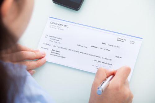 Woman signs a check over to a third party.