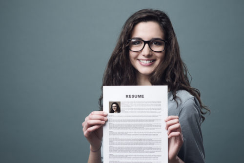 A young woman holds up her resume