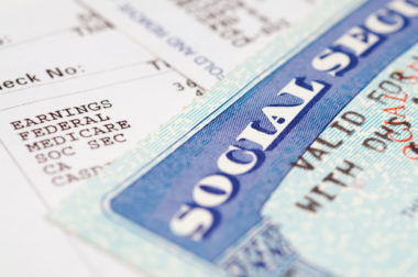 A Social Security card on top of Social Security check stubs.