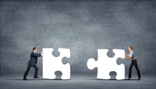 business people pushing puzzle pieces together