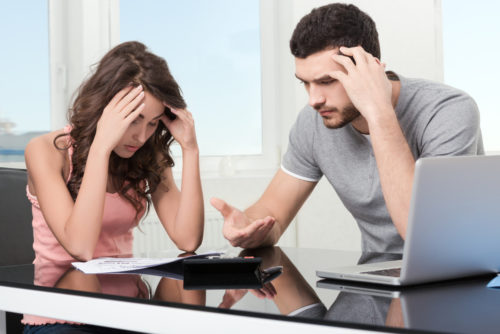 Man and woman upset looking at credit card statement.