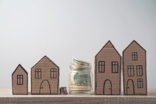 Cardboard home cutouts, a jar of money, and a stack of change