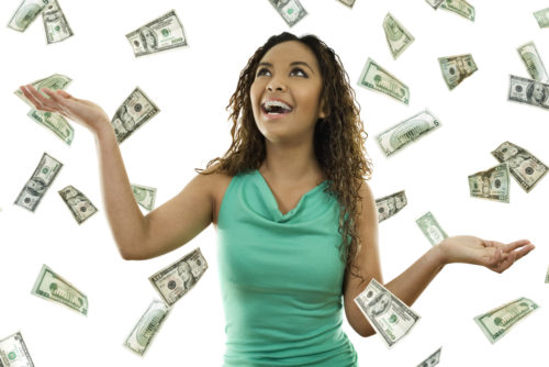 Woman in a green shirt standing with open arms amidst falling (raining) money.