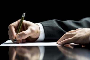 Man wearing suit writing a letter by hand