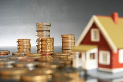 Stacks of coins next to a toy home