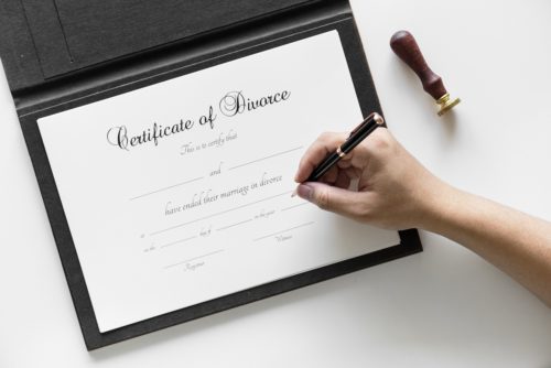 A hand signing a certificate of divorce.