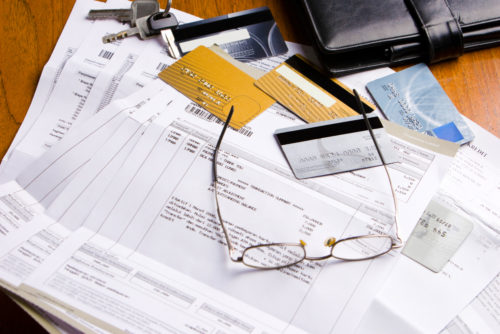 A photo of a desk with credit cards, glasses, a wallet, and credit card statements spread across it.