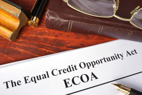 Photo of a desk with books and papers on it, the top paper reading “Equal Credit Opportunity Act: ECOA”.