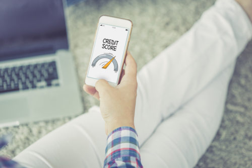 Unidentified person holds a phone looking at a credit score gauge.