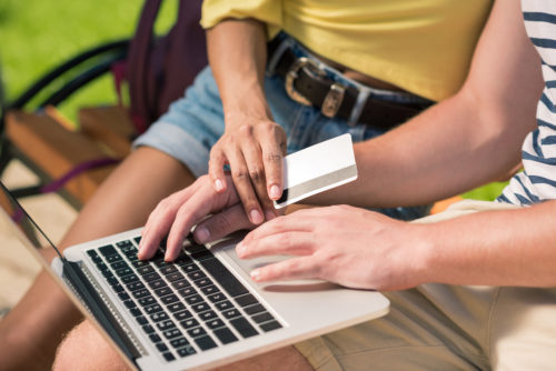 Couple shopping online with card in hand.