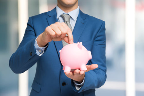 A man in a blue suit puts a quarter in a piggy bank.