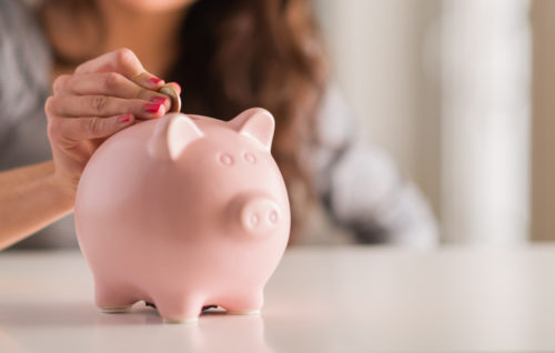 Woman puts money in a piggy bank for savings.