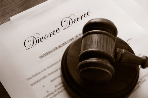 A document titled “Divorce Decree” resting on a wooden table. On top of the document is a judge’s gavel.