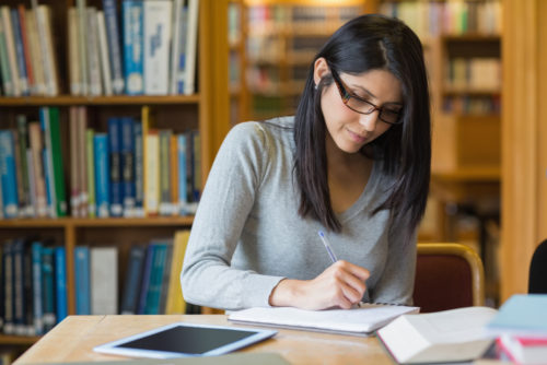 Hispanic woman studying in a college library.