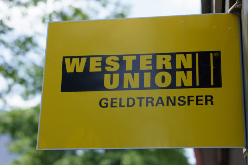 The Western Union name and logo on a yellow signpost.