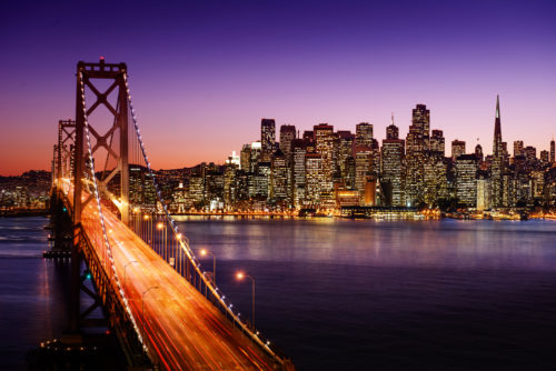 San Francisco’s Bay Bridge and downtown skyline at sunset.