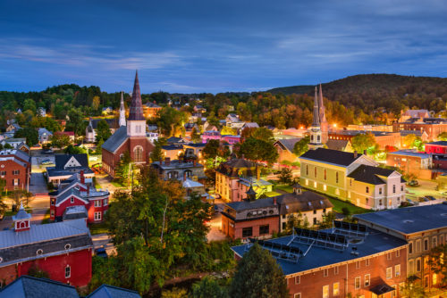 A skyline photograph of Montpelier, Vermont at dusk, lights twinkling on the buildings.