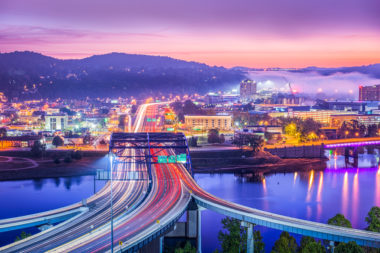 A sunset skyline view of Charleston, West Virginia, with mountains and rolling fog in the background. Long exposure.