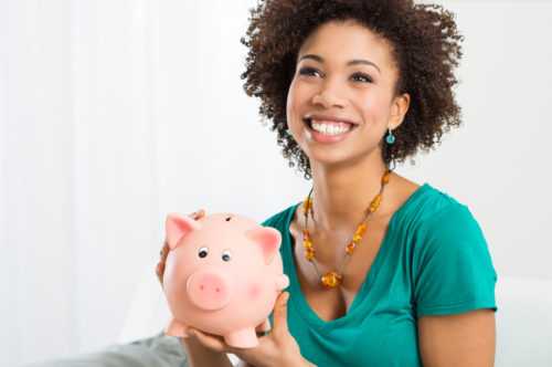 A smiling woman holds a piggy bank.