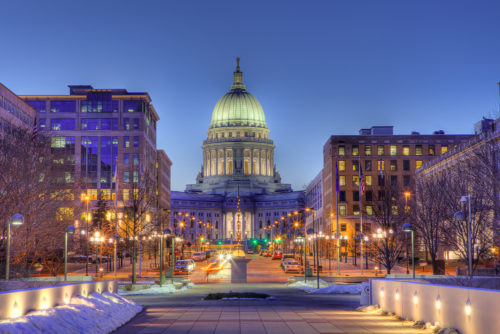A skyline photograph of Madison, Wisconsin at dusk, with snow and twinkling lights.