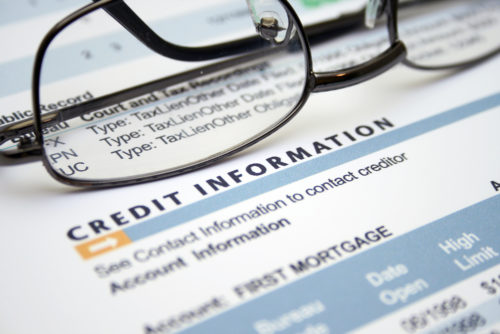 An image of eyeglasses sitting atop a credit information report.