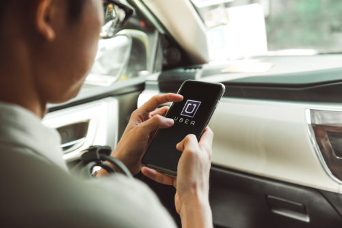 A man uses the Uber app on his smartphone and sits in a car