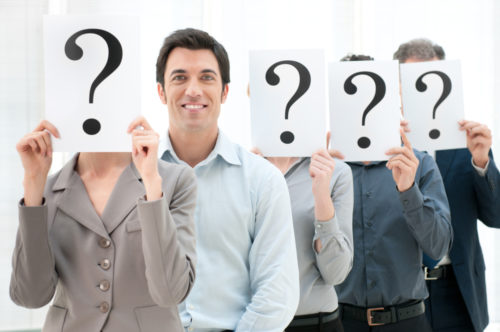 A job candidate standing out in a line of people holding question marks in front of their faces