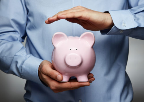 Man holding piggy bank with one hand hovering over the top.
