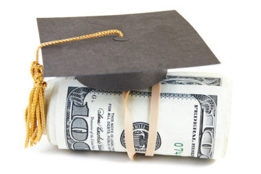 A graduation cap sits on top of a roll of 100 dollar bills.