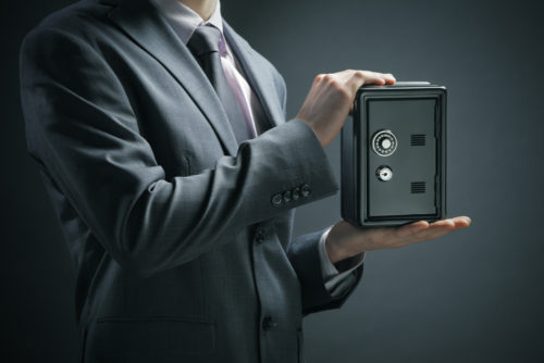 A man holds a small safe in his hands to put his savings into.