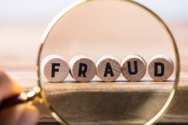 A magnifying glass putting into focus the word "fraud."