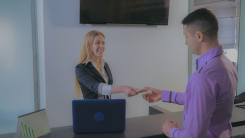 A woman handing a man cash in exchange for a check he gave her.