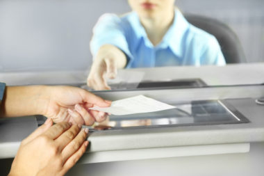 A woman at a check cashing store receives a check from another woman.