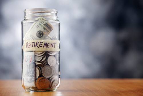 A jar filled with coins and cash labeled “retirement.”