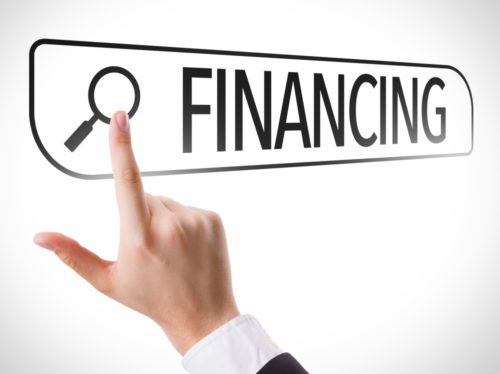 A hand with a finger approaching a button of a graphic that depicts the button that says "Financing."