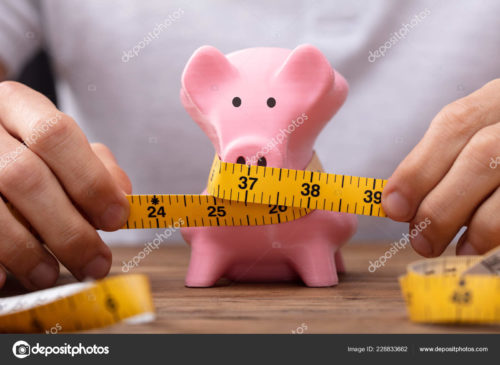A man’s hands wrapping measuring tape around a skinny piggy bank.