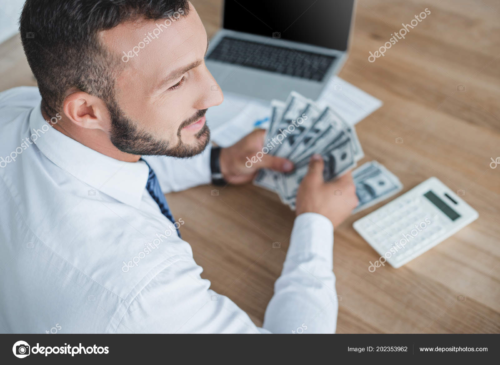 A man in a shirt and tie with a laptop and calculator counts money.