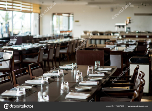 Empty formal restaurant seating with tableware and glasses prepared.