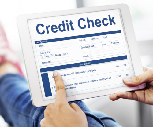 A woman holds a tablet with a screen that shows a credit check website.