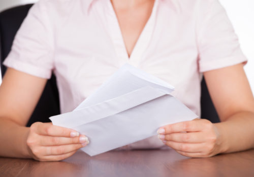 A woman places a business letter into an envelope.