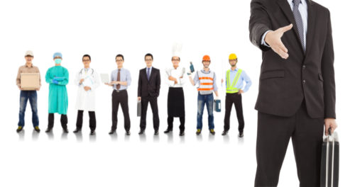 A line of people with attire for various jobs stands behind a business man extending his hand.