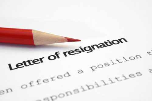 A red colored pencil sits on top of a letter of resignation.