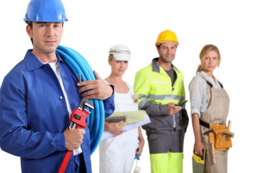 A group of people all in trade job attire including a plumber, electrician, and more.