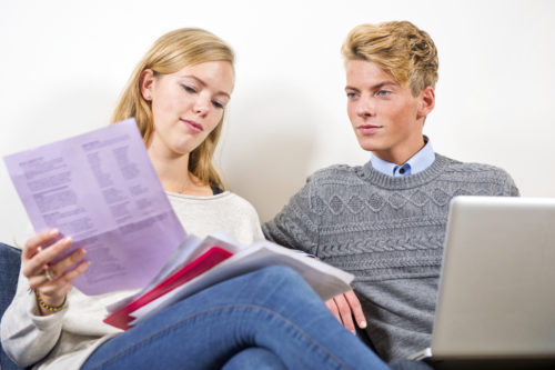 A couple sits down with bank statements and a laptop to determine if they want to set up a joint bank account.