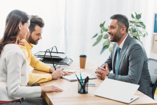 A man and woman signing paperwork at the desk of a wealth manager